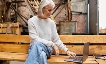 A mature woman working her weekend job on her laptop on a park bench